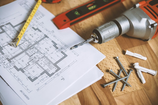  a floor plan on a table next to drills and screws